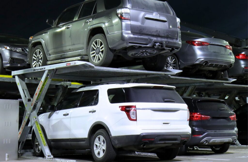 Two levels of Autostacker parking lifts in a commercial car park, with SUVs parked above and below in single bays
